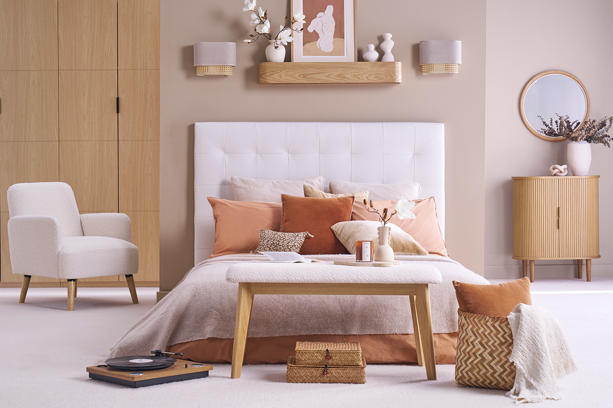 Chambre avec deux appliques en lin beige et cannage rotin au-dessus du lit.