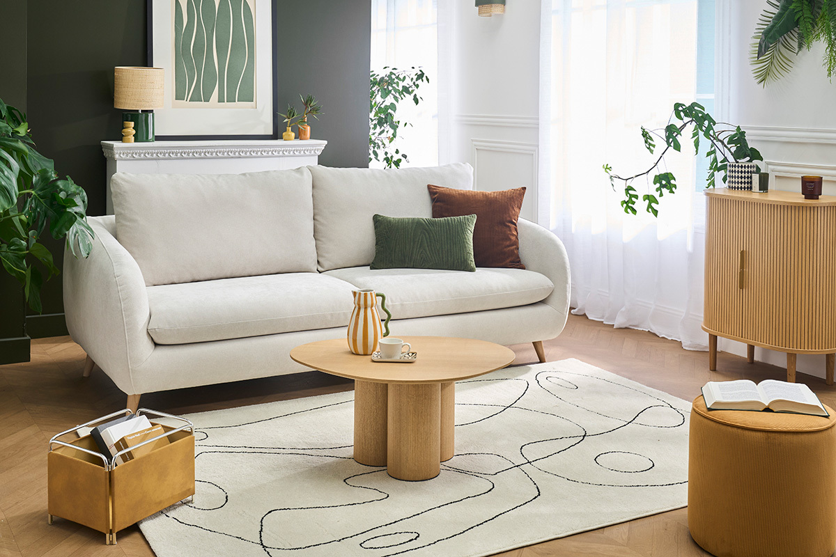 Canap� convertible 3-4 places beige en tissu effet velours, avec coussins d�coratifs, dans un salon moderne.