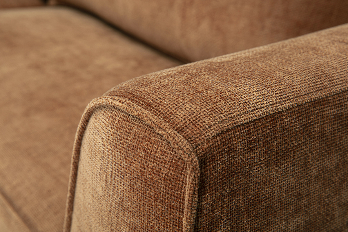 Gros plan sur l'accoudoir d'un canap� en tissu effet velours terre br�l�e.