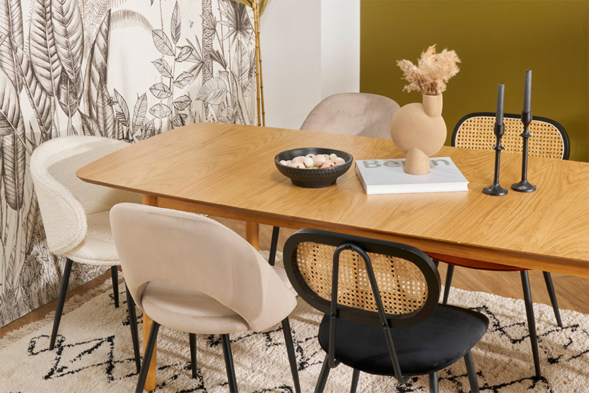 Chaises design en velours et rotin autour d'une table en bois clair.