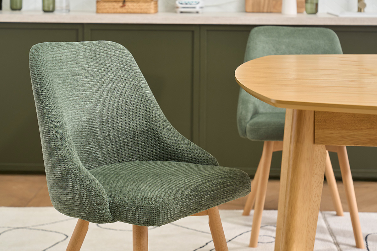Chaises en tissu vert kaki et pieds en bois clair, vue de trois quarts, pr�s d'une table en bois.