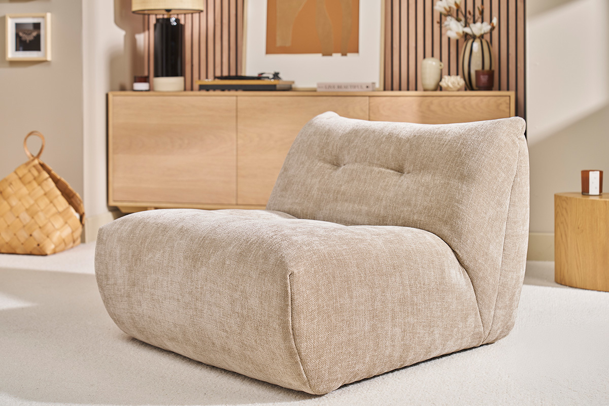 Fauteuil lounge en tissu taupe effet velours dans un salon.