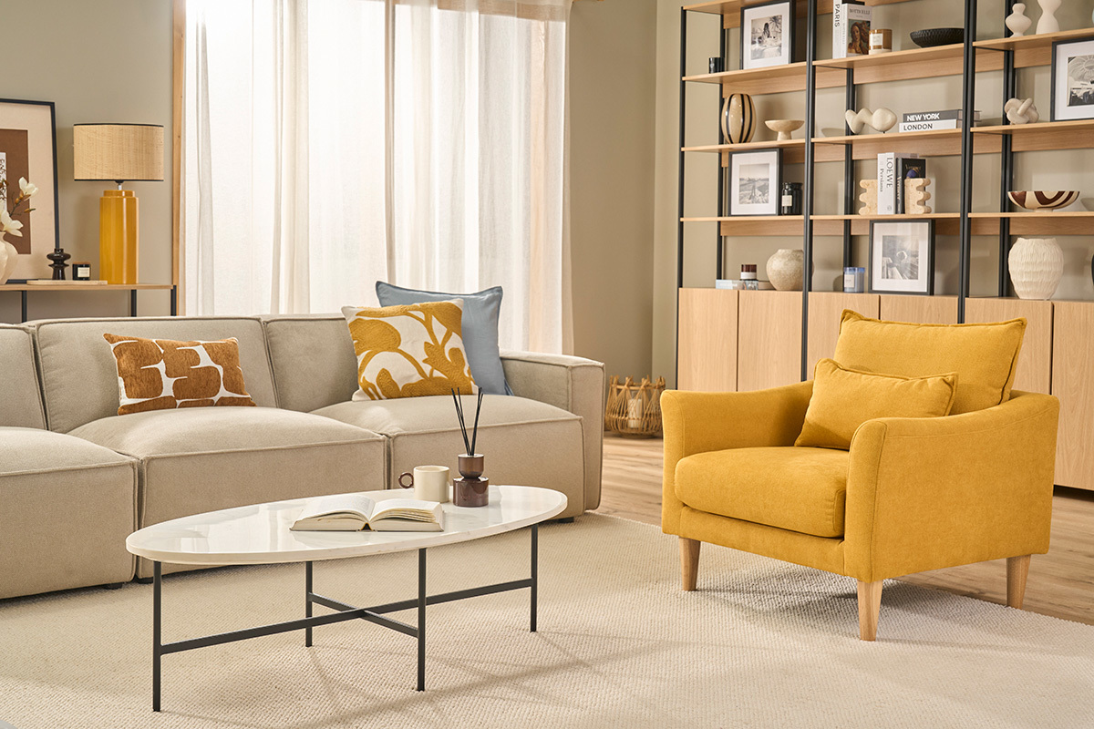 Fauteuil scandinave KATE en velours jaune moutarde, avec coussins, dans un salon �l�gant.