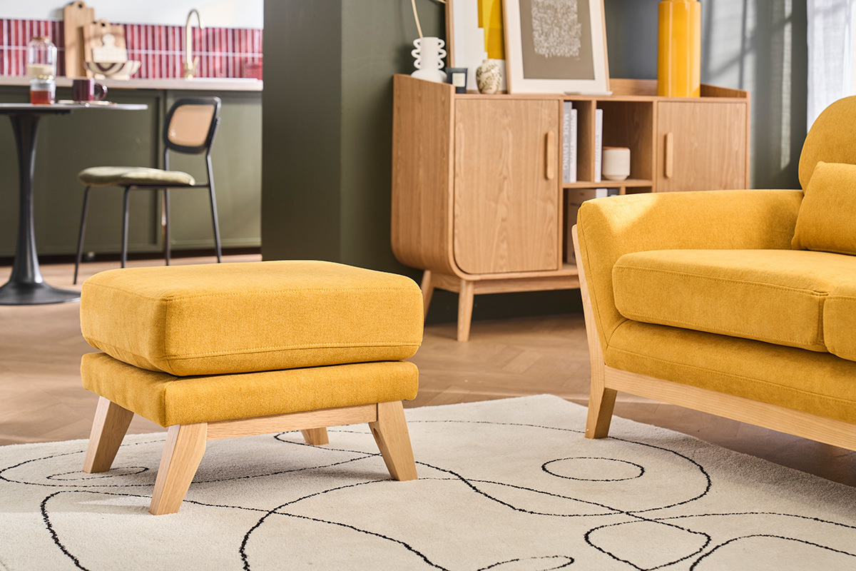 Pouf repose-pieds jaune moutarde et bois clair dans un salon.