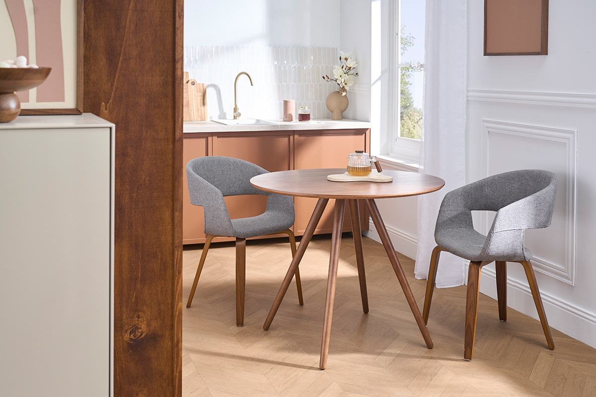 Table � manger ronde ARTIK en noyer avec deux chaises gris, vue d'ensemble dans une salle � manger moderne.