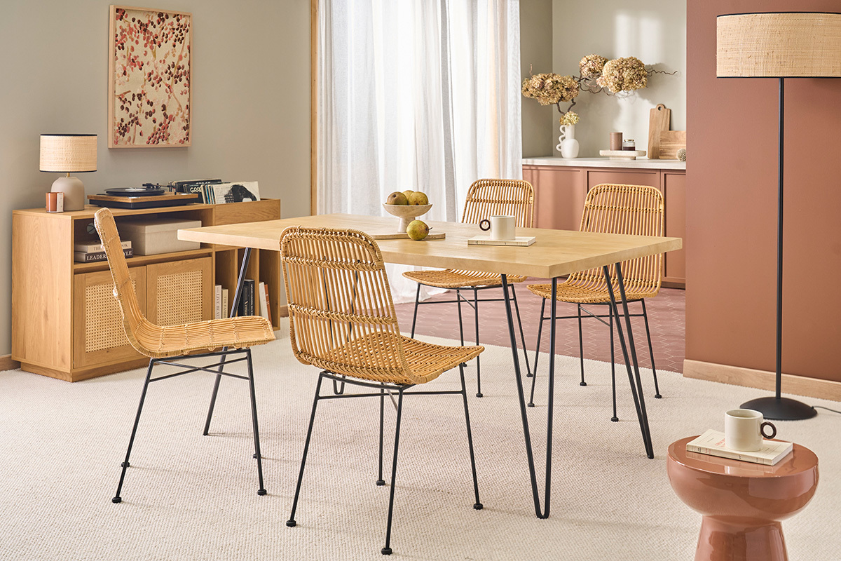 Table � manger en bois avec pieds en m�tal noir, entour�e de chaises en rotin, vue de trois quarts.