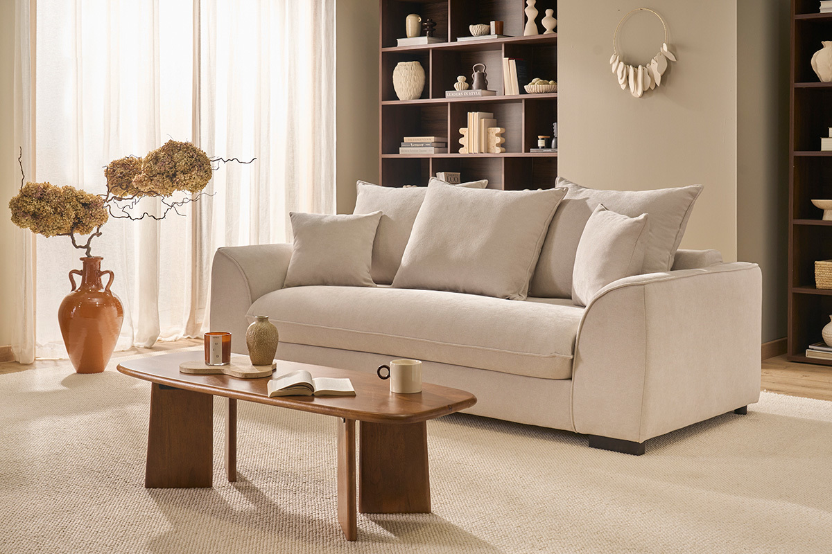 Table basse en bois de manguier devant un canap� beige, avec objets d�coratifs autour.