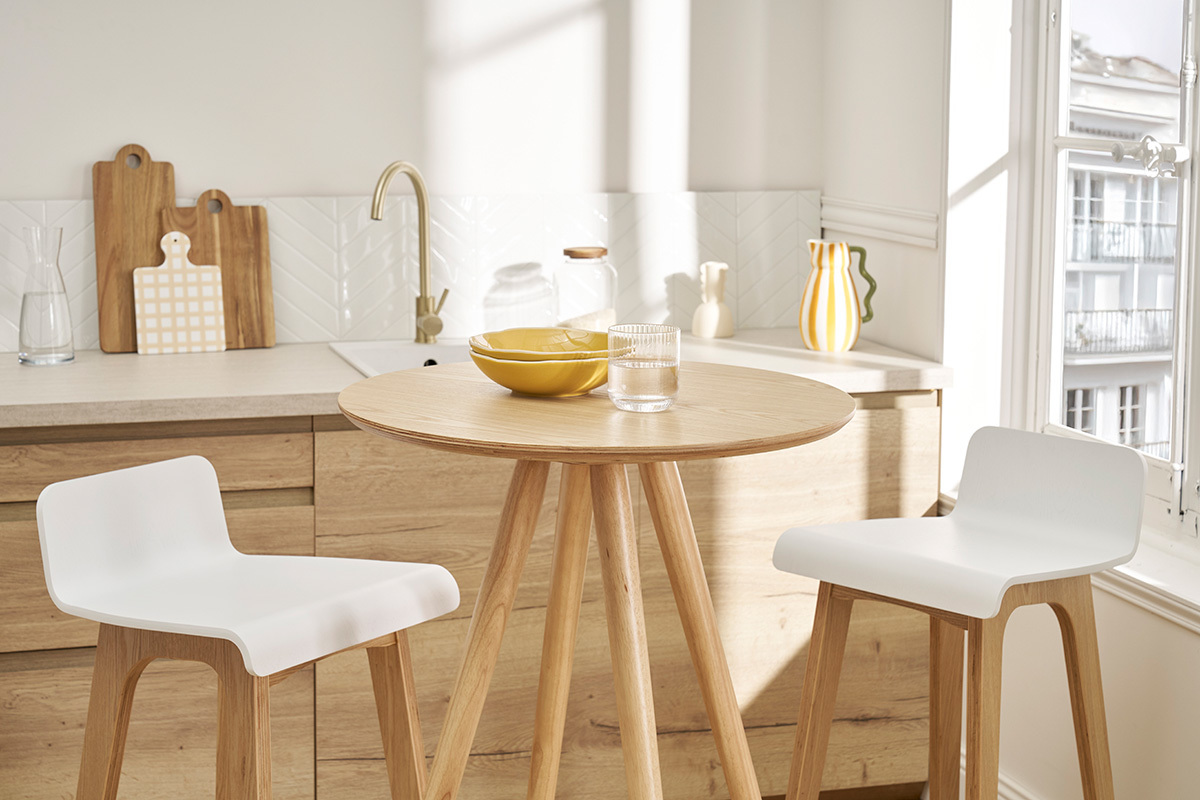 Table de bar ronde scandinave de 60 cm avec chaises blanches et d�cor dans une cuisine lumineuse.