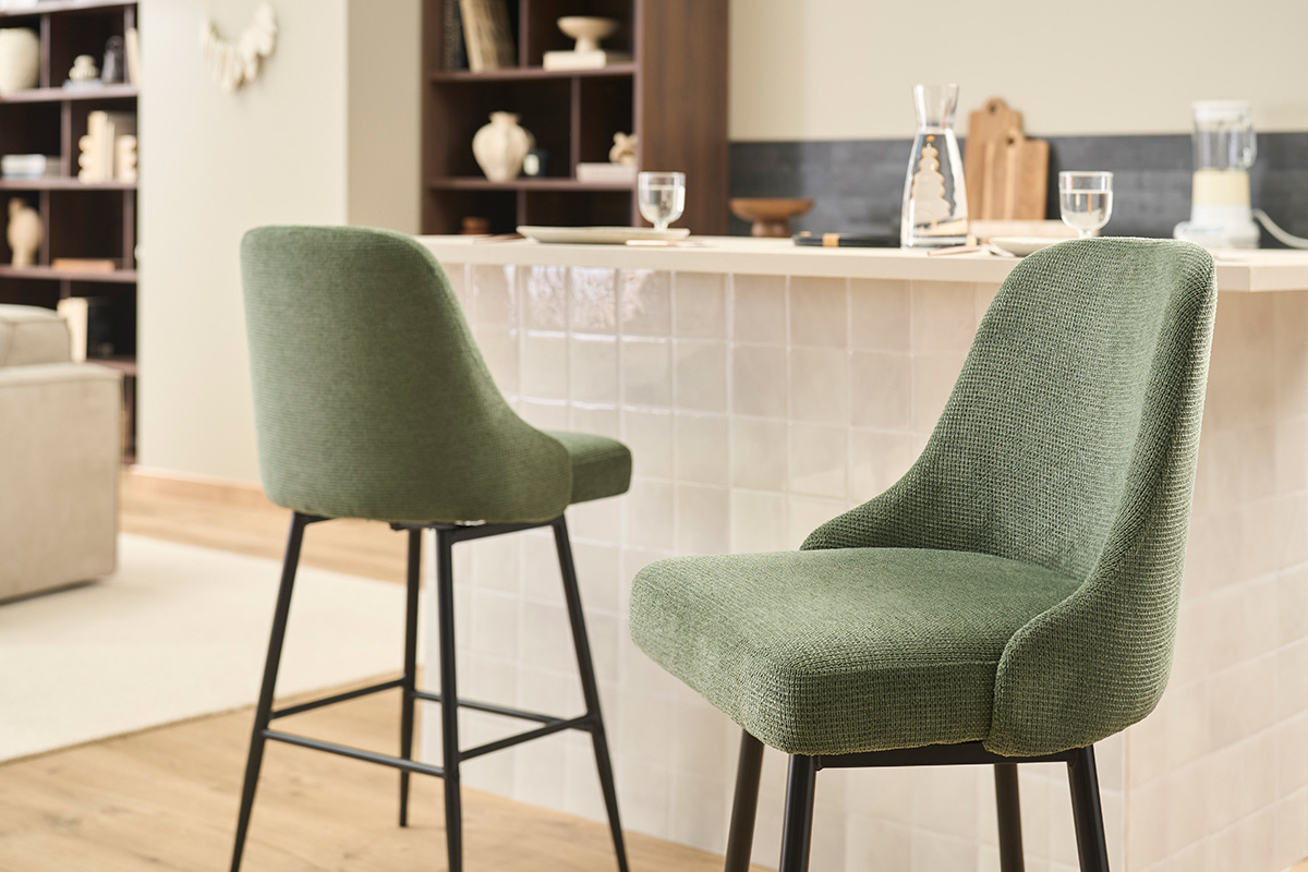 Tabourets de bar en tissu vert kaki et m�tal noir, vus de c�t�, pr�s d'un comptoir de cuisine.