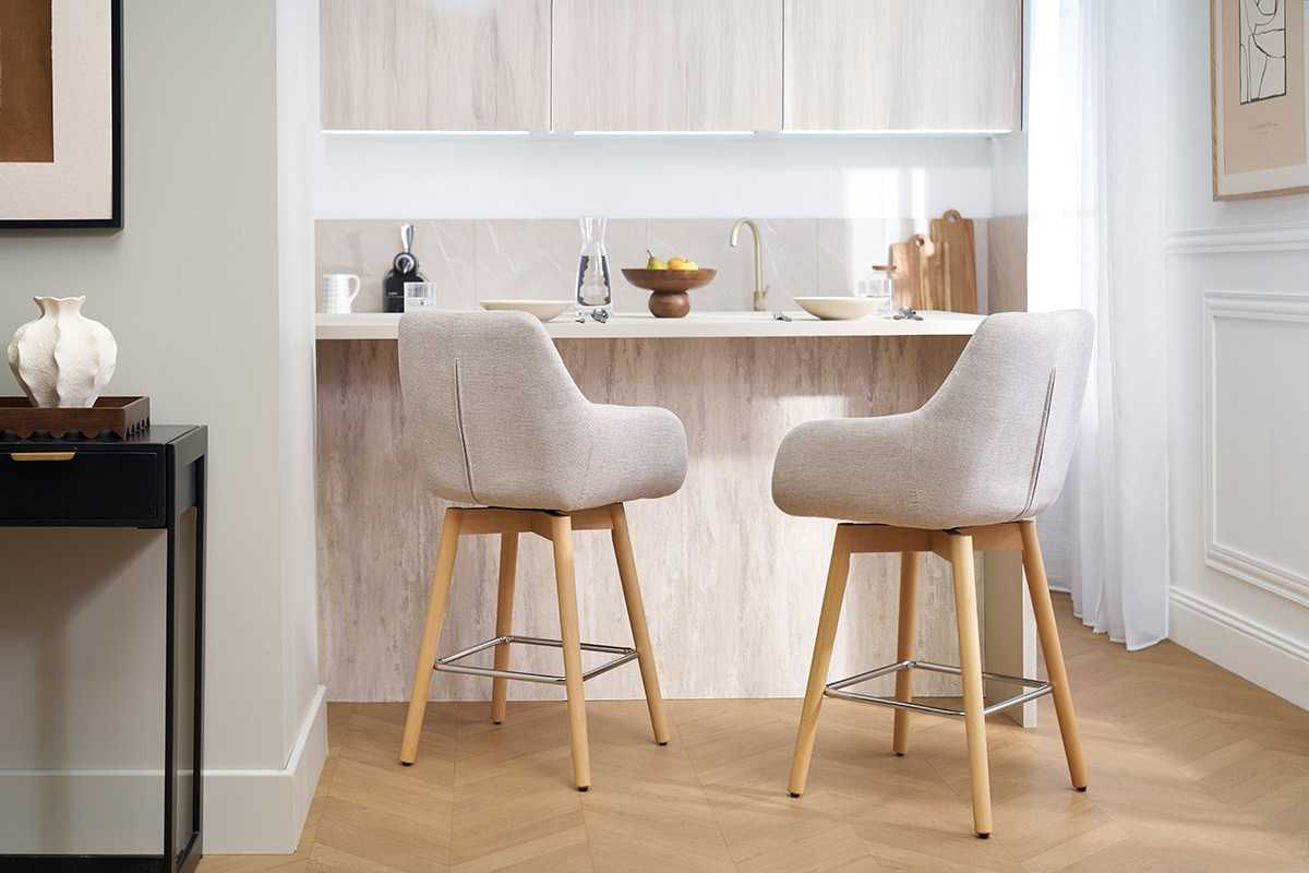 Deux tabourets de bar scandinaves beiges devant un comptoir de cuisine.