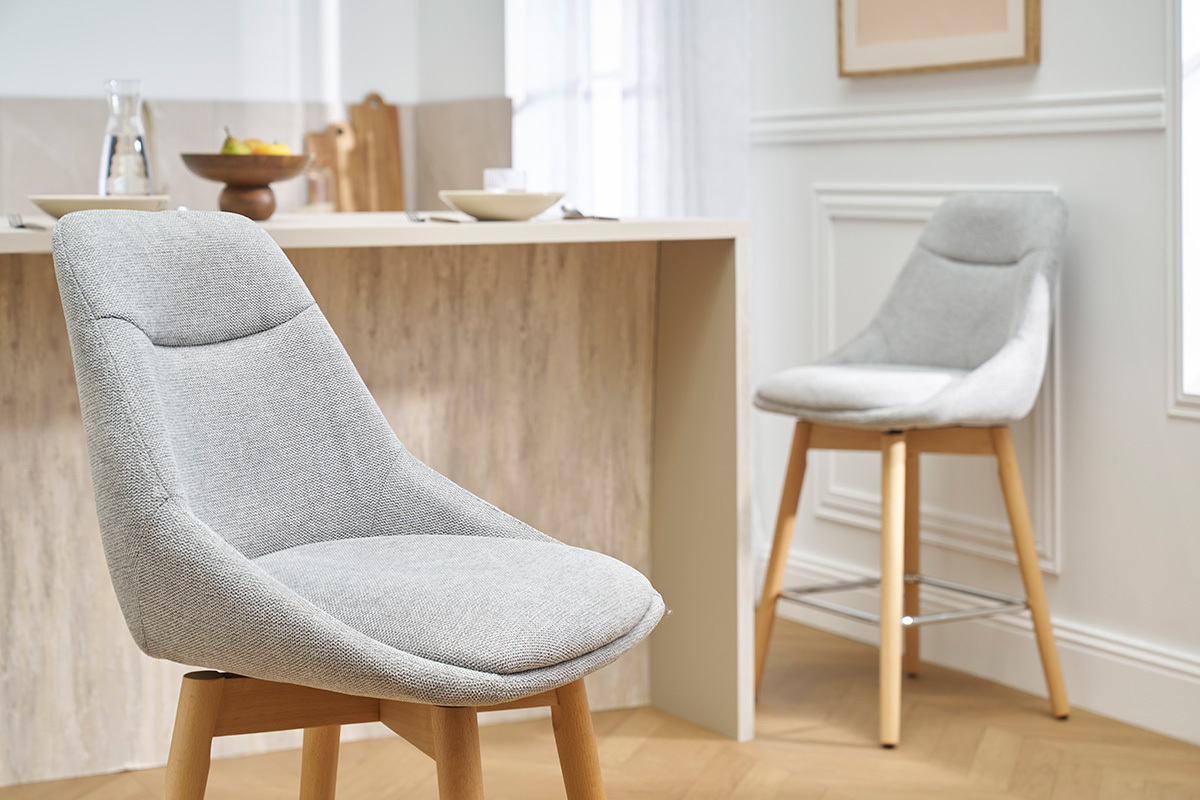 Tabourets de bar scandinaves en tissu gris et bois clair, angle montrant un comptoir en arri�re-plan.