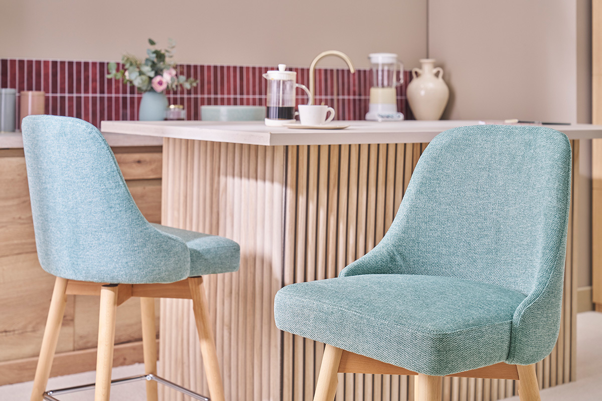 Tabourets de bar verts c�ladon en tissu et bois, devant un comptoir moderne.