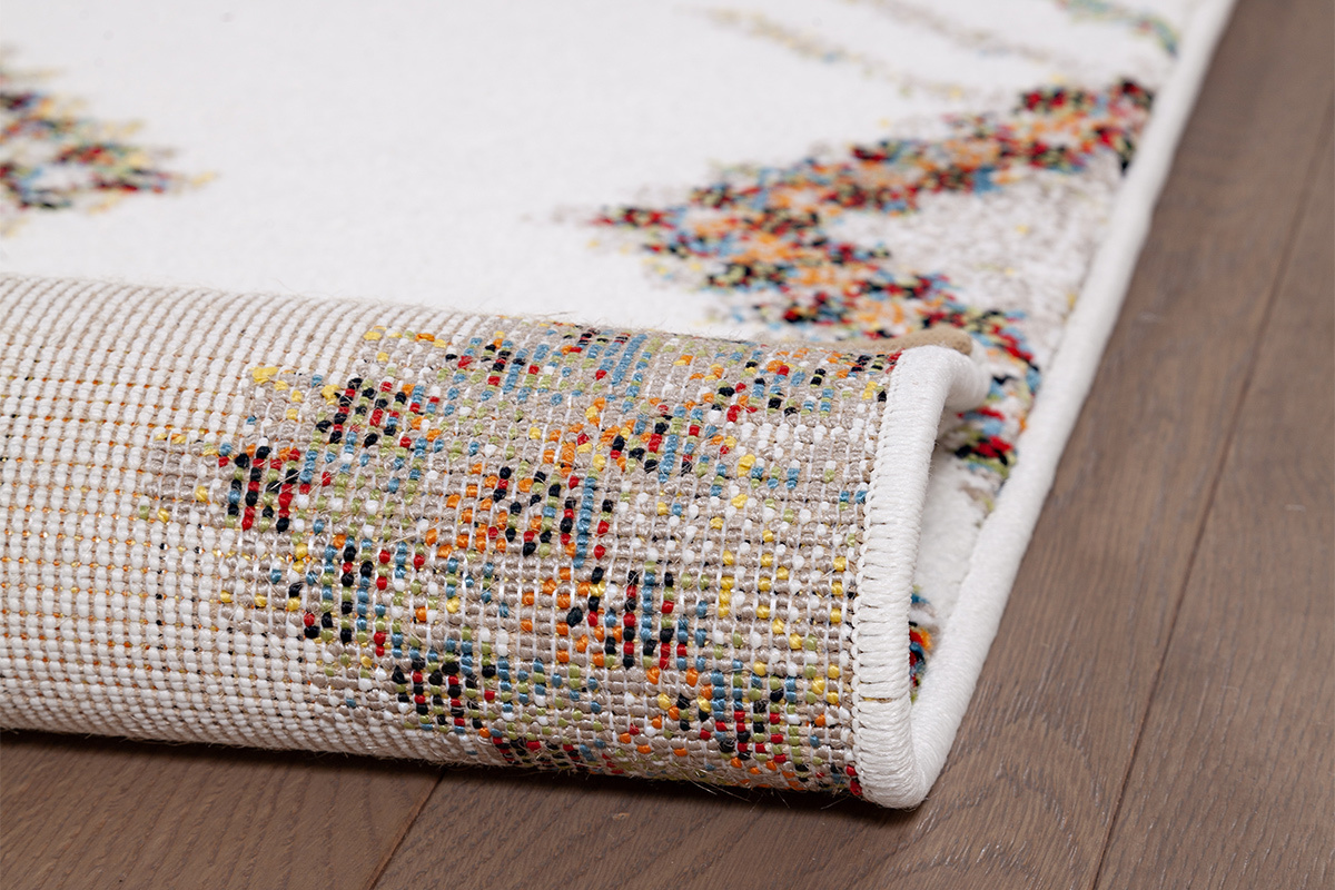 Vue rapproch�e du bord d'un tapis � motifs color�s sur parquet.
